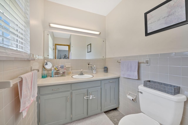 bathroom featuring tile patterned floors, vanity, toilet, and tile walls