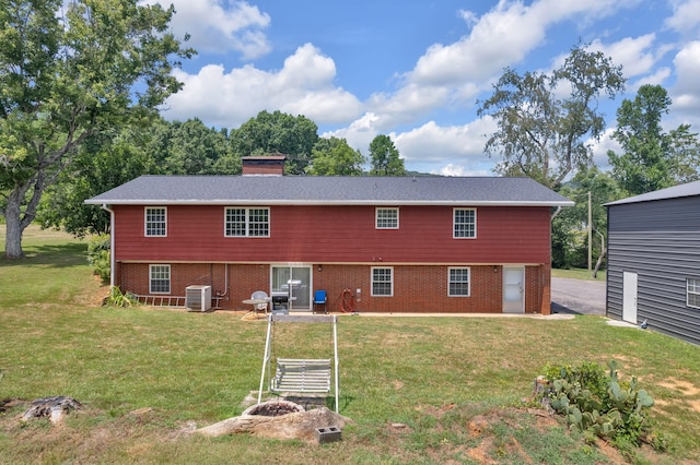 rear view of property with central AC and a lawn