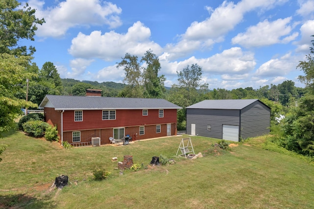 rear view of house featuring a lawn, an outbuilding, cooling unit, and a garage