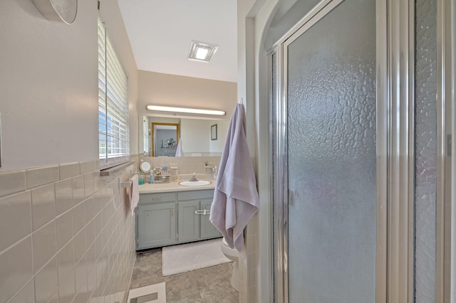 bathroom with vanity, a shower with door, and tile walls