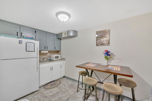 kitchen with gray cabinetry, decorative backsplash, white appliances, and sink