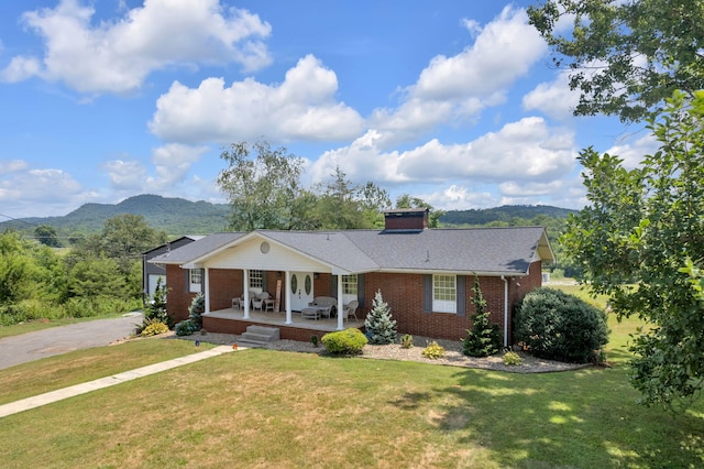 single story home with a mountain view, a front lawn, and covered porch