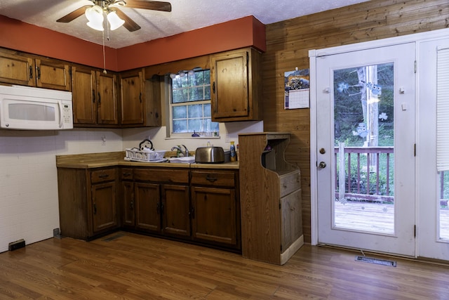 3084 Sherm Mountain Rd, Sneedville, TN 37869 - kitchen featuring white microwave, a ceiling fan, wood finished floors, healthy amount of natural light, and wooden walls
