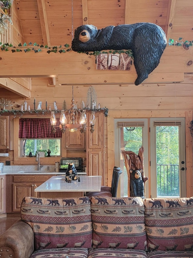 kitchen featuring beam ceiling, sink, high vaulted ceiling, wooden walls, and wood ceiling