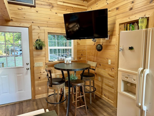 dining area with dark hardwood / wood-style flooring and wooden walls