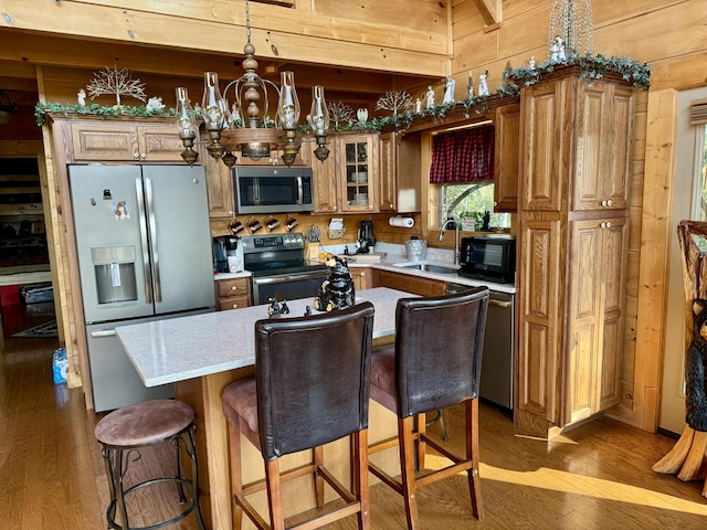 kitchen with stainless steel appliances, a kitchen island, wood walls, and sink