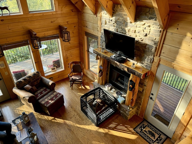 living room with beam ceiling, high vaulted ceiling, a wealth of natural light, and a stone fireplace