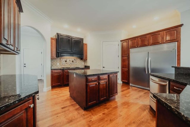 118 Luxury Ln, Dandridge, TN 37725 - kitchen featuring light wood-style flooring, stainless steel appliances, decorative backsplash, dark stone counters, and arched walkways