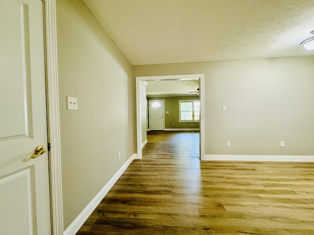 hall featuring wood-type flooring and a textured ceiling