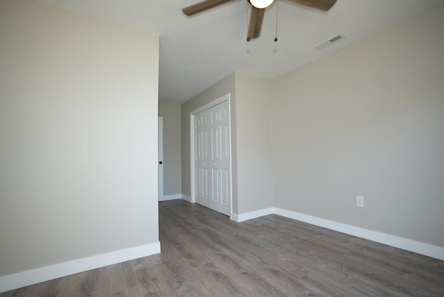 unfurnished room with wood finished floors, baseboards, a ceiling fan, and visible vents