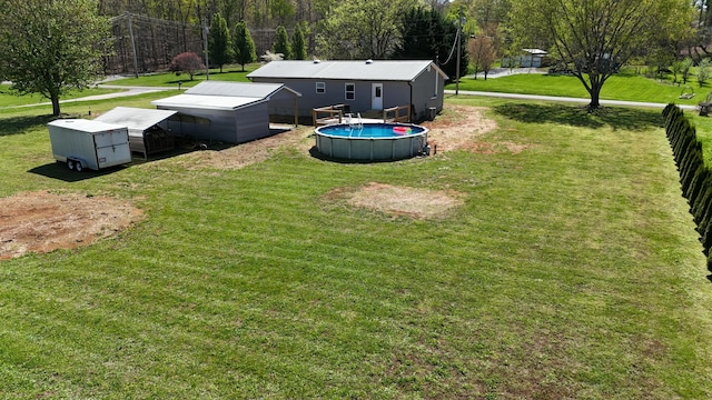 view of yard featuring an outdoor pool, fence, and an outdoor structure