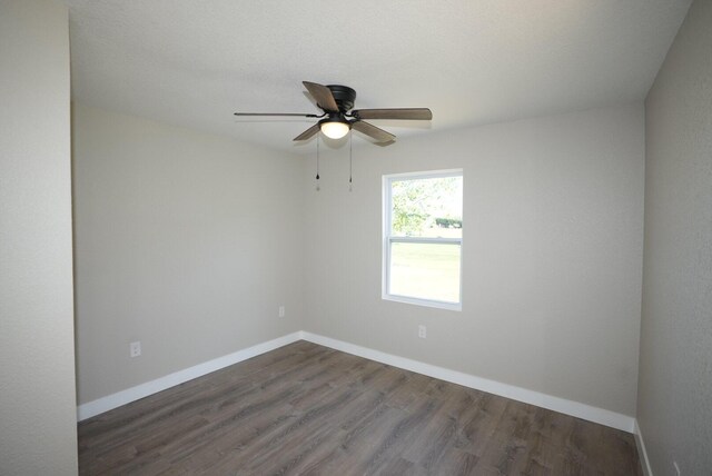 empty room featuring dark wood-type flooring, baseboards, and a ceiling fan