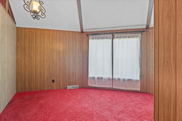 carpeted empty room featuring a textured ceiling and wood walls