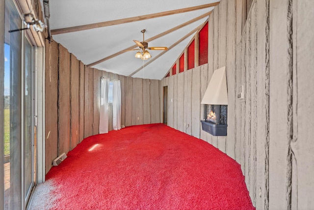 unfurnished room featuring ceiling fan, wood walls, carpet, and vaulted ceiling with beams