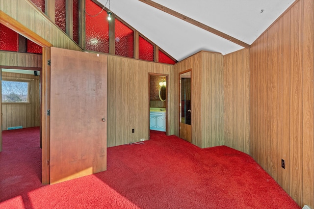 carpeted spare room featuring lofted ceiling with beams and wood walls