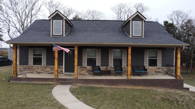 cape cod home with a front yard and covered porch