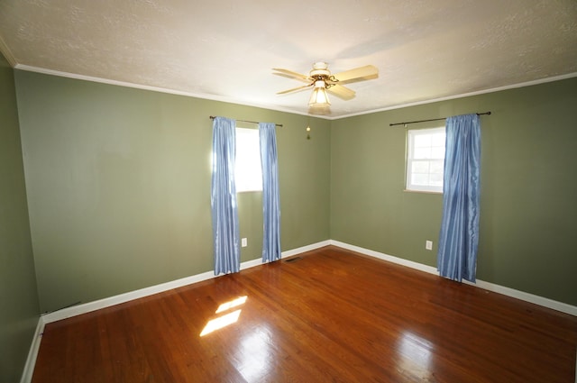 spare room with visible vents, ceiling fan, baseboards, ornamental molding, and wood finished floors