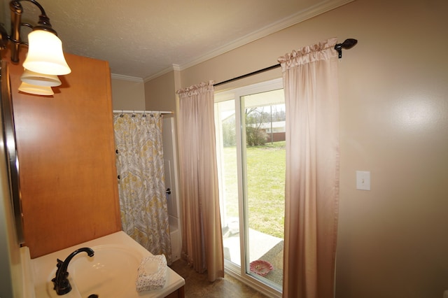 full bath with a textured ceiling, crown molding, and a sink