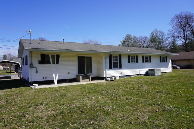 back of house featuring a detached carport, a yard, and central AC unit