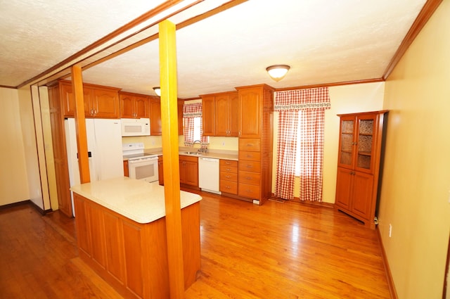 kitchen with a sink, white appliances, light wood finished floors, and light countertops