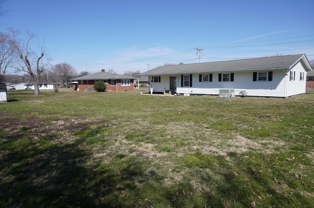 rear view of house featuring central air condition unit and a lawn