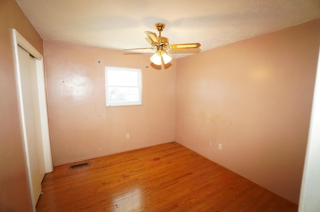 unfurnished bedroom featuring a closet, visible vents, a ceiling fan, and light wood-style floors