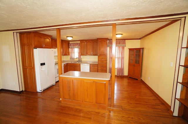 kitchen with white appliances, dark wood finished floors, ornamental molding, a sink, and light countertops