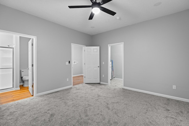 unfurnished bedroom with a textured ceiling, carpet floors, connected bathroom, and baseboards