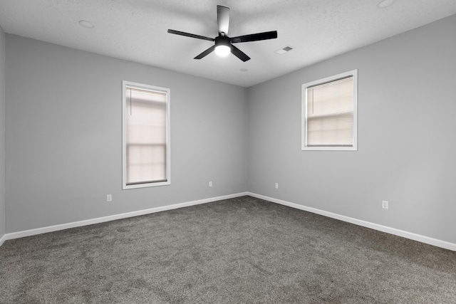 empty room with visible vents, dark carpet, and a wealth of natural light