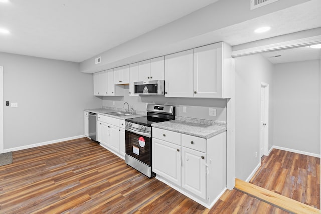 kitchen featuring stainless steel appliances, dark wood finished floors, white cabinets, and a sink