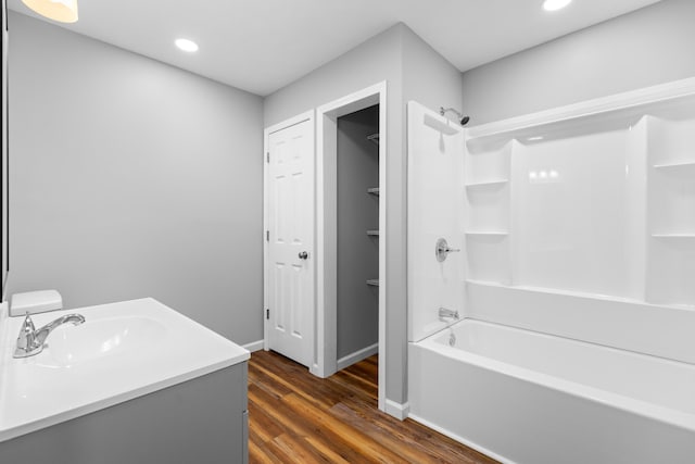 full bathroom with baseboards, wood finished floors, vanity, shower / washtub combination, and recessed lighting