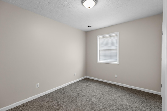 empty room with a textured ceiling, carpet floors, and baseboards