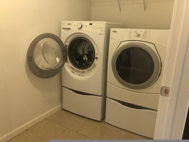 laundry room featuring washing machine and clothes dryer and light tile patterned flooring