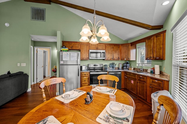 kitchen featuring pendant lighting, vaulted ceiling with beams, appliances with stainless steel finishes, and an inviting chandelier