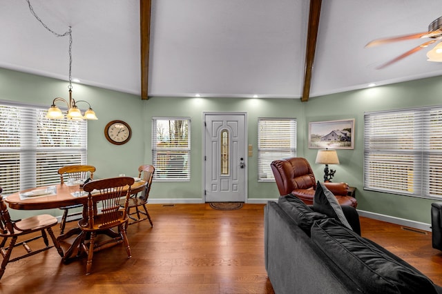 dining room with hardwood / wood-style flooring, lofted ceiling with beams, plenty of natural light, and ceiling fan with notable chandelier