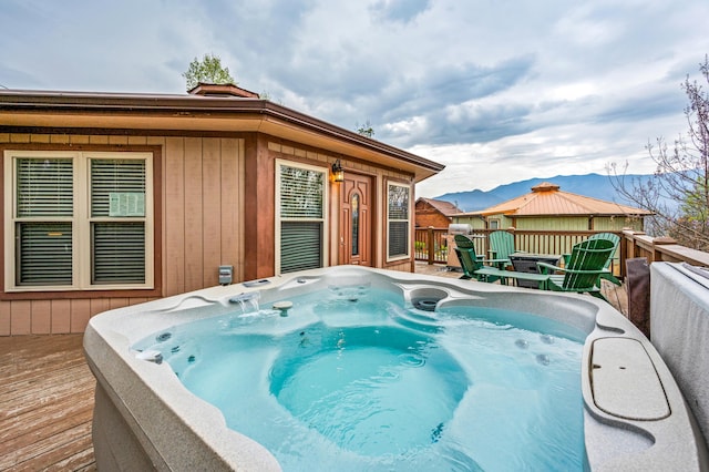 view of swimming pool with a deck with mountain view and a hot tub