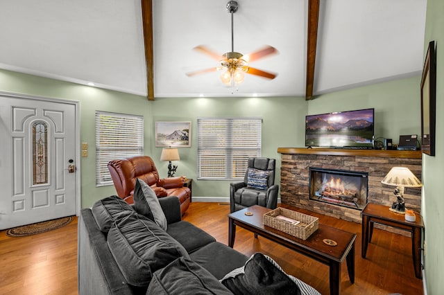 living room featuring a fireplace, light wood-type flooring, vaulted ceiling with beams, and ceiling fan