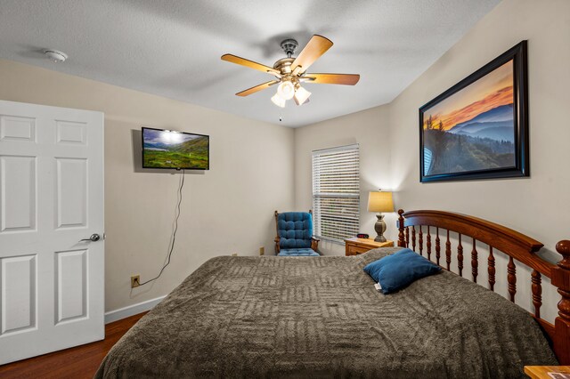 bedroom with a textured ceiling, dark hardwood / wood-style flooring, and ceiling fan