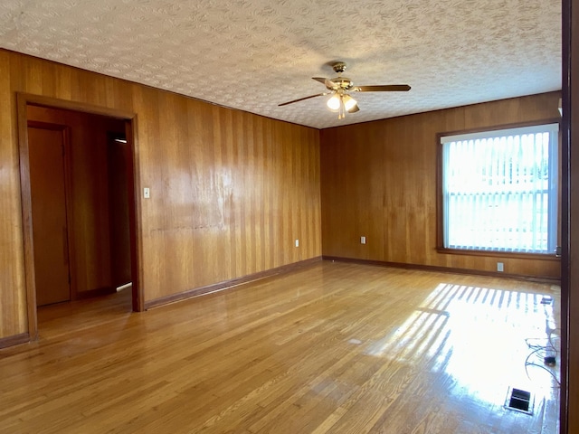 unfurnished room with ceiling fan, light hardwood / wood-style flooring, and a textured ceiling