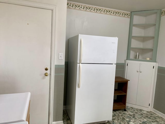 kitchen featuring white fridge and tile walls