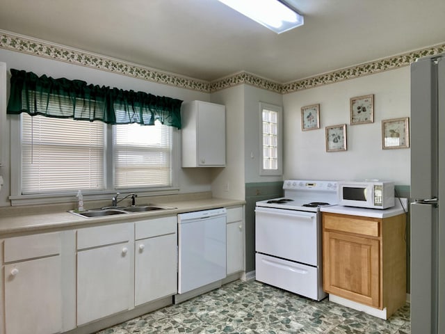 kitchen with white cabinetry, sink, and white appliances