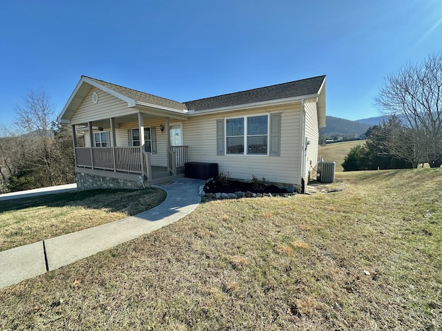 view of front of property with covered porch, central air condition unit, and a front yard