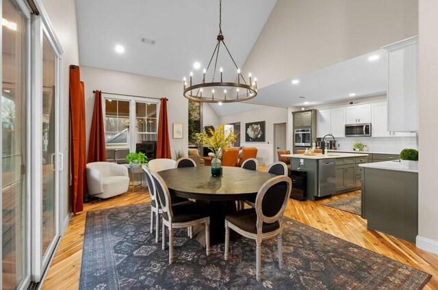 dining room featuring a notable chandelier, high vaulted ceiling, light wood-type flooring, visible vents, and recessed lighting