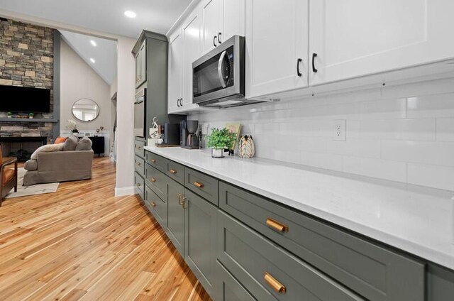 kitchen with light countertops, backsplash, light wood finished floors, appliances with stainless steel finishes, and open floor plan