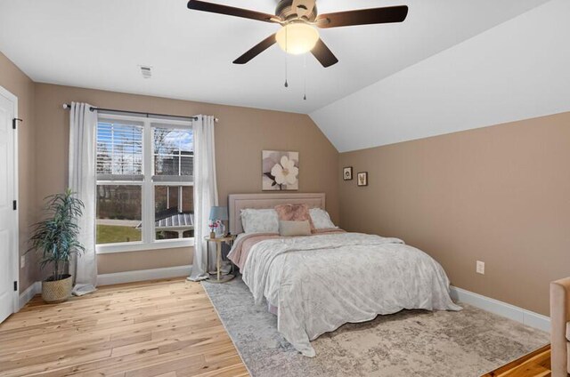 bedroom featuring visible vents, baseboards, ceiling fan, light wood-style floors, and vaulted ceiling