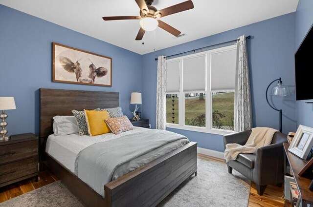 bedroom with baseboards, wood finished floors, and a ceiling fan