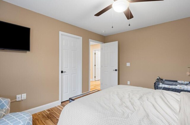 bedroom featuring baseboards, light wood-style flooring, and a ceiling fan