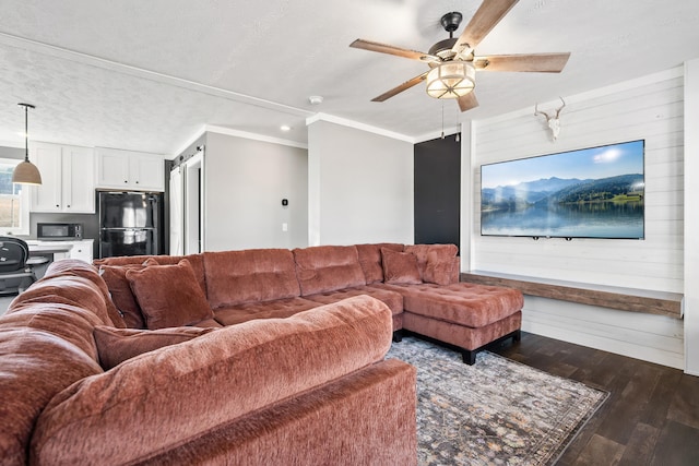 living room with a ceiling fan, dark wood-type flooring, wood walls, a textured ceiling, and crown molding