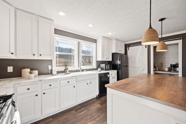 kitchen featuring a sink, a barn door, black appliances, and white cabinets