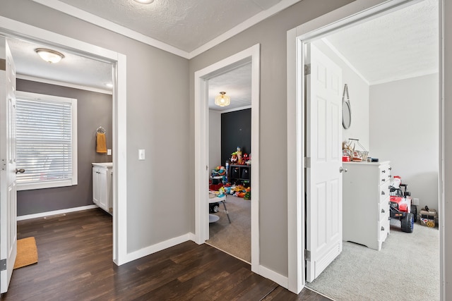 hallway featuring baseboards, dark wood-type flooring, crown molding, and a textured ceiling